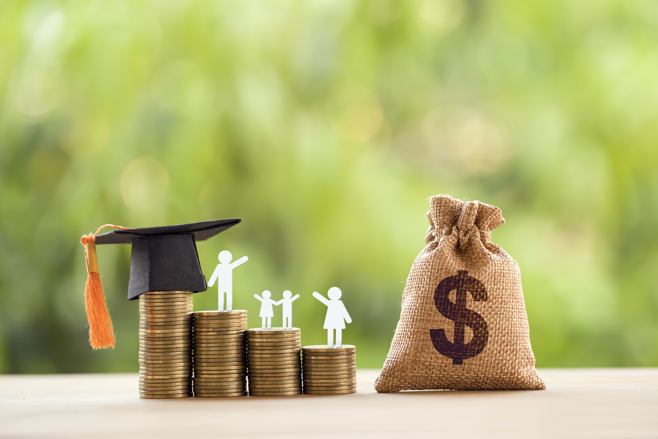 Black graduation cap, hat, student and kid, rows of rising coins, white clock on a table, natural green background. Public school funding, education funding, financial concept